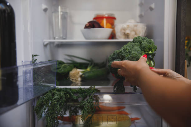 Person placing vegetables in fridge